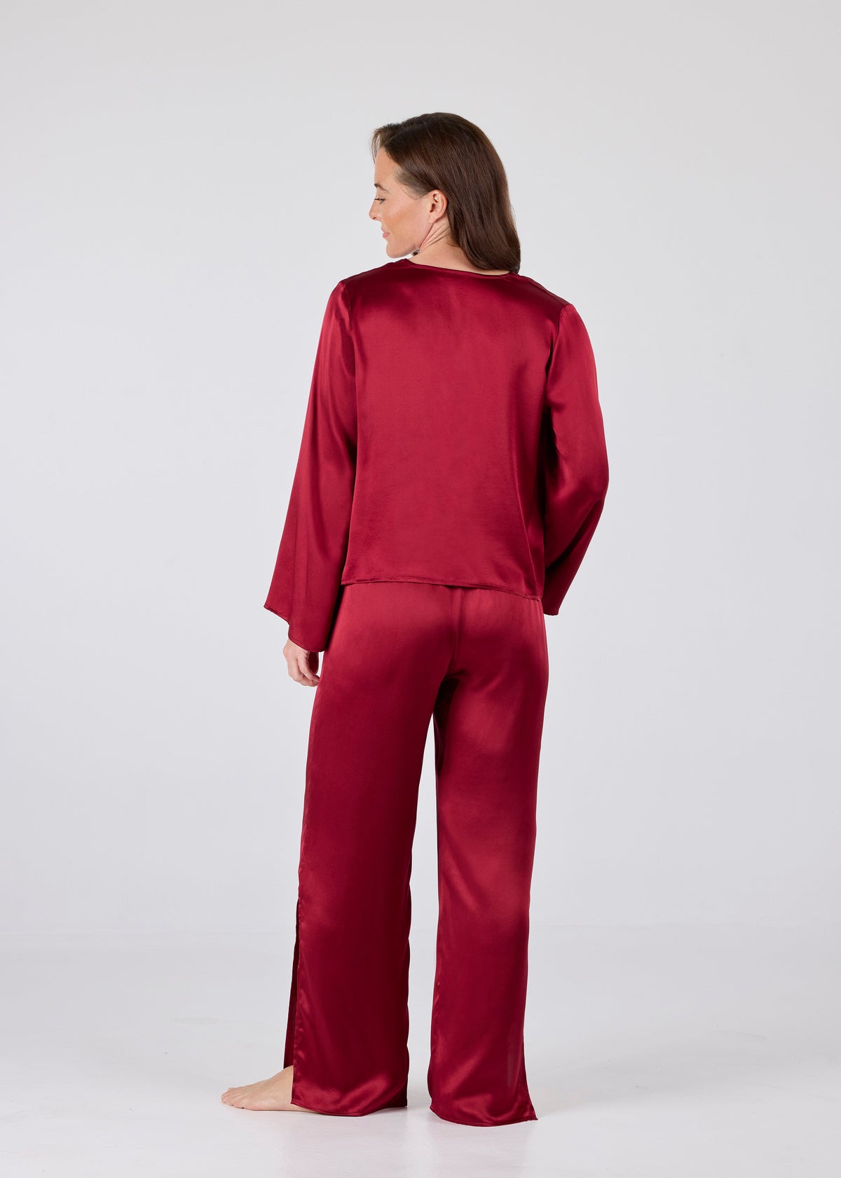 Back view of model wearing Amelia Set in Dark Red: Model wearing A.ROSE Amelia Set in dark red washable silk – adjustable tie‑front long sleeve top paired with flowy pants featuring high side slits and side pockets. Subtly sexy and timeless loungewear and/or sleepwear.