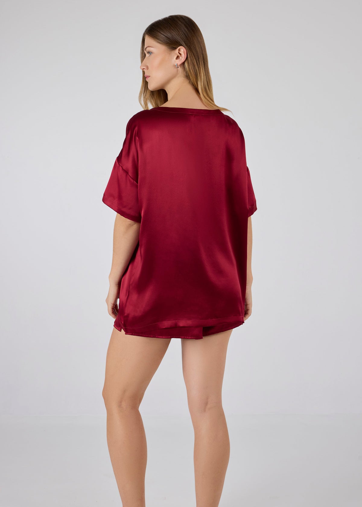 Back view of model wearing A.ROSE Luna Set in dark red washable silk – oversized boyfriend-style tee with chest pocket paired with relaxed-fit shorts featuring subtle side slits and a soft elastic waistband. Perfect for elevated lounging or bridesmaid gifting. Loungewear and/or sleepwear.