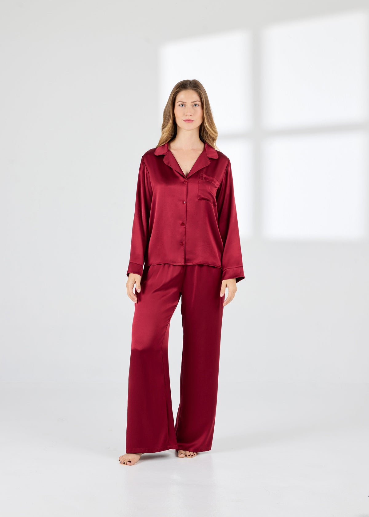 Model wearing A.ROSE Victoria Set in dark red washable silk – long-sleeve button-down top with chest pocket paired with flowy wide-leg pants and soft elastic waistband. Timeless loungewear and sleepwear.