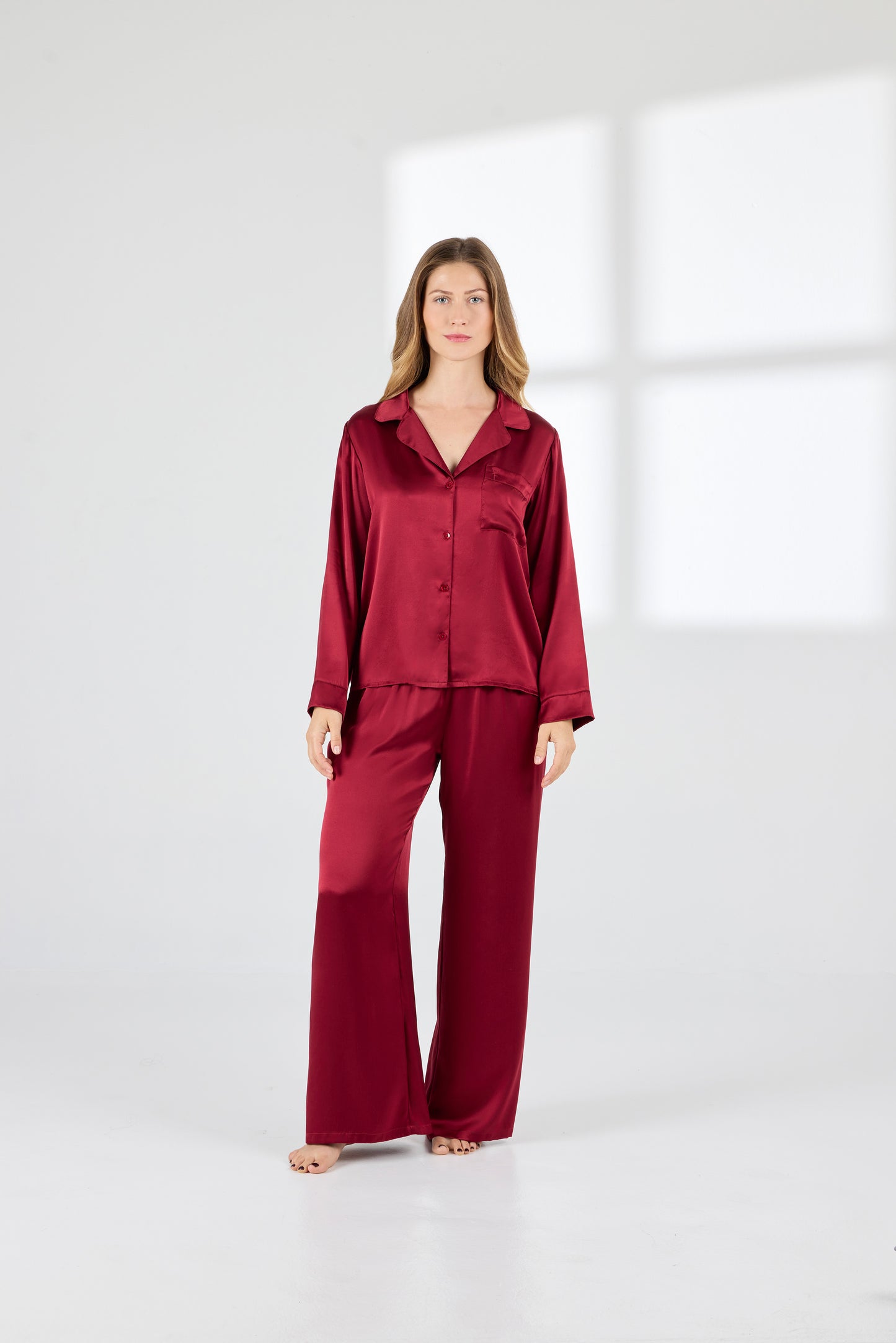 Model wearing A.ROSE Victoria Set in dark red washable silk – long-sleeve button-down top with chest pocket paired with flowy wide-leg pants and soft elastic waistband. Timeless loungewear and sleepwear.