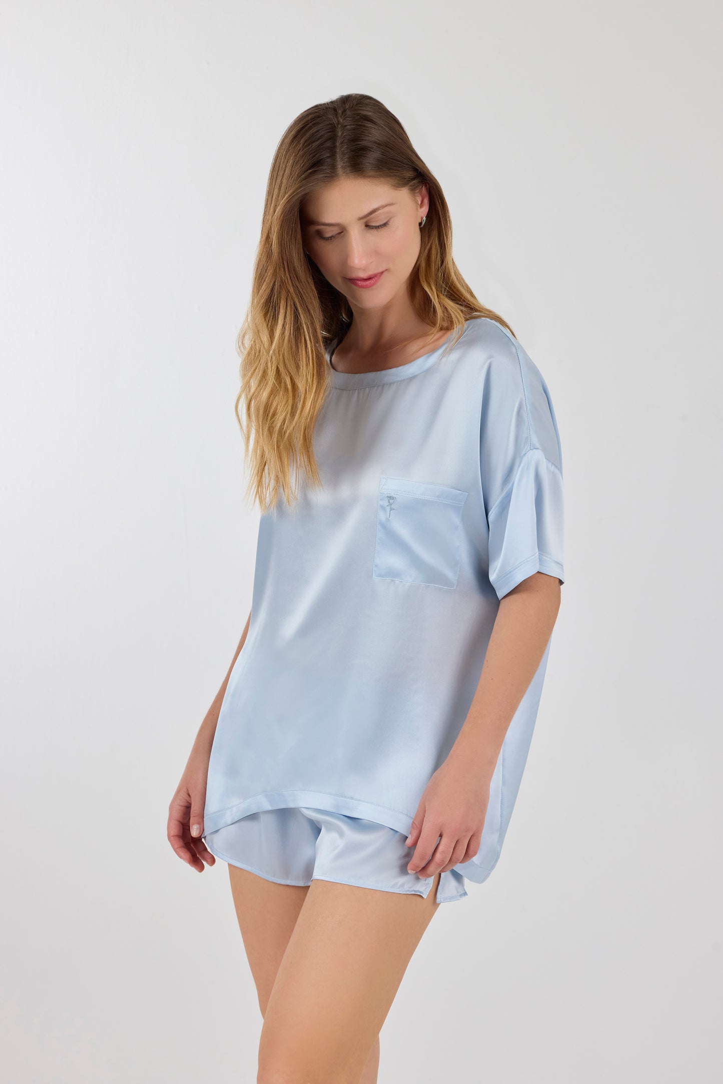 Model wearing A.ROSE Luna Set in ice blue washable silk – oversized boyfriend-style tee with chest pocket paired with relaxed-fit shorts featuring subtle side slits and a soft elastic waistband. Perfect for elevated lounging or bridesmaid gifting. Loungewear and/or sleepwear.