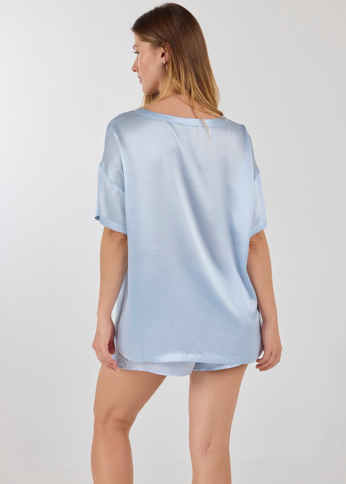 Back view of model wearing A.ROSE Luna Set in ice blue washable silk – oversized boyfriend-style tee with chest pocket paired with relaxed-fit shorts featuring subtle side slits and a soft elastic waistband. Perfect for elevated lounging or bridesmaid gifting. Loungewear and/or sleepwear.